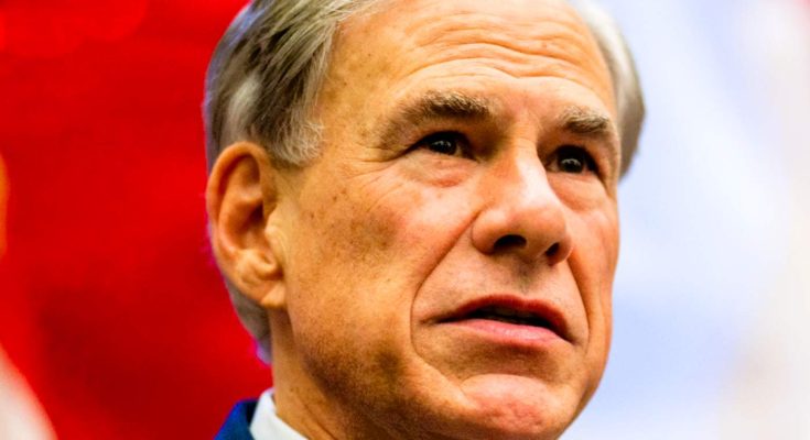 Close-up of a man with gray hair wearing a blue suit jacket and white collared shirt