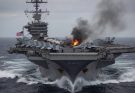 Aircraft carrier with fire and black smoke on deck, American flag visible, choppy ocean