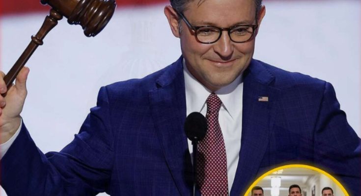 Man in blue suit holding a gavel at a podium with a red and white background, inset