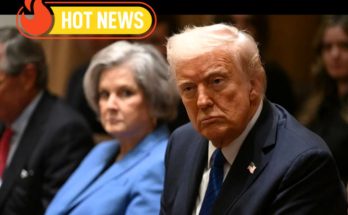 Donald Trump seated in a formal setting with a serious expression, wearing a dark suit