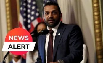 A man in a dark suit and tie speaking at a podium with microphones, with an American