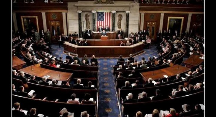 Interior view of a large legislative chamber with many people seated in rows, an