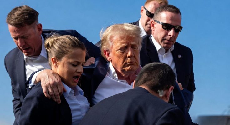Donald Trump surrounded by Secret Service agents, one with an arm around a female agent