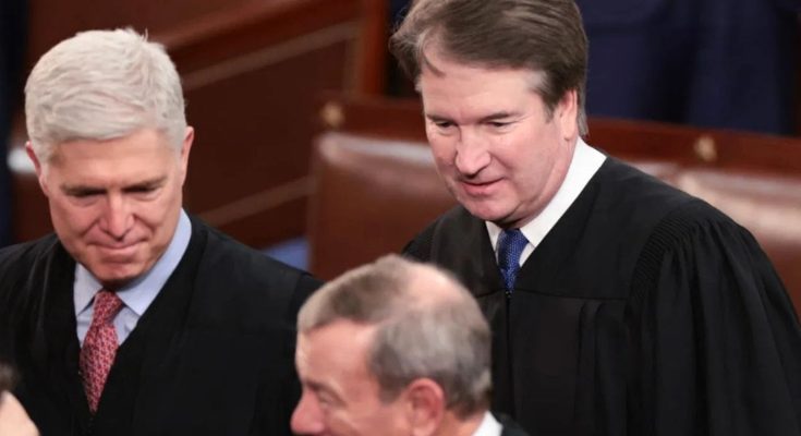 A line of law enforcement officers in riot gear with shields faces a woman holding a