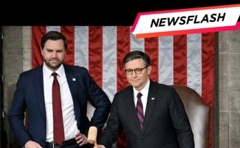 Two men in suits stand in front of an American flag backdrop, one holding a gavel, with