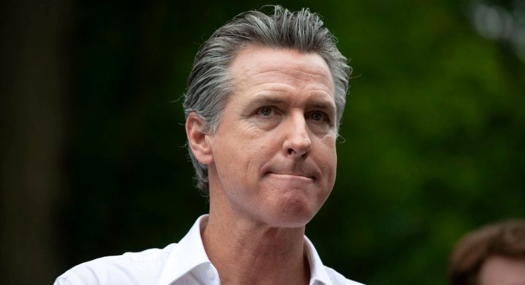 Gavin Newsom wearing a white collared shirt with gray hair, looking to the side with a