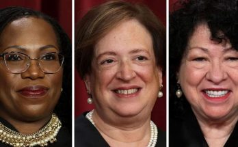 Three women in formal attire with jewelry, side by side against a red background