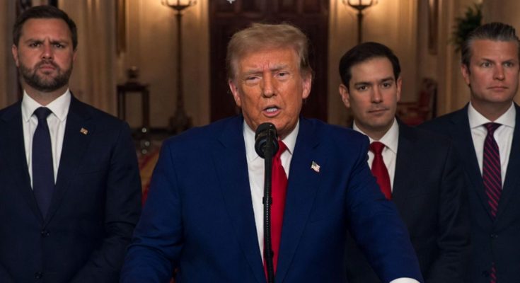 Donald Trump speaking at a podium with a microphone, wearing a blue suit and red tie
