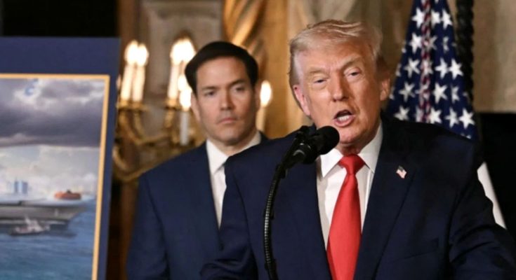 Donald Trump speaking at a podium with a microphone, wearing a dark suit and red tie