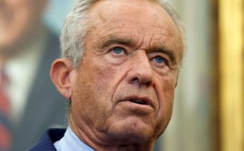 Close-up of Robert F. Kennedy Jr. with gray hair, wearing a pinstripe suit and light