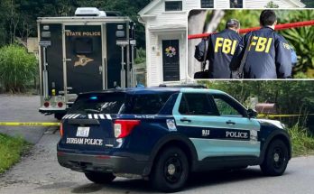 Police vehicles including a Durham Police SUV and State Police truck parked near a house
