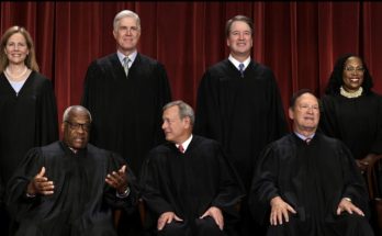 Group photo of nine Supreme Court justices in black robes against a red curtain
