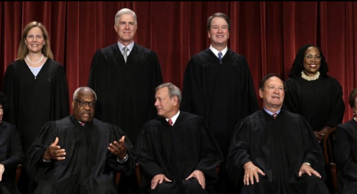 Group photo of nine Supreme Court justices in black robes against a red curtain