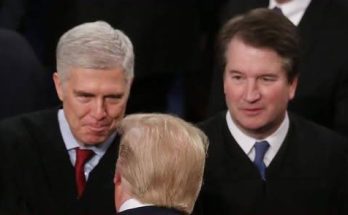 Donald Trump seen from behind with Neil Gorsuch and Brett Kavanaugh in judicial robes