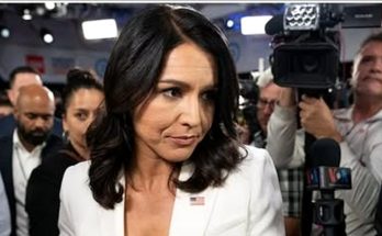 woman in white suit surrounded by media at event