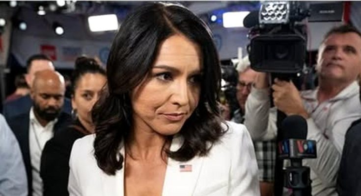 woman in white suit surrounded by media at event