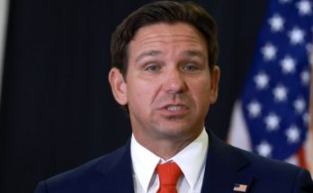 ron DeSantis speaking at podium with Florida seal and American flag behind him, text asks