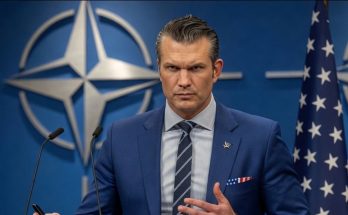 pete Hegseth speaks at NATO podium with breaking news headline about resignation