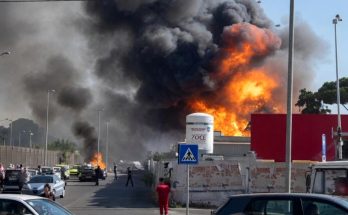 industrial fire sends black smoke skyward as emergency responders and 118 ambulance