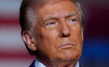 serious man in suit with flag background, focused expression