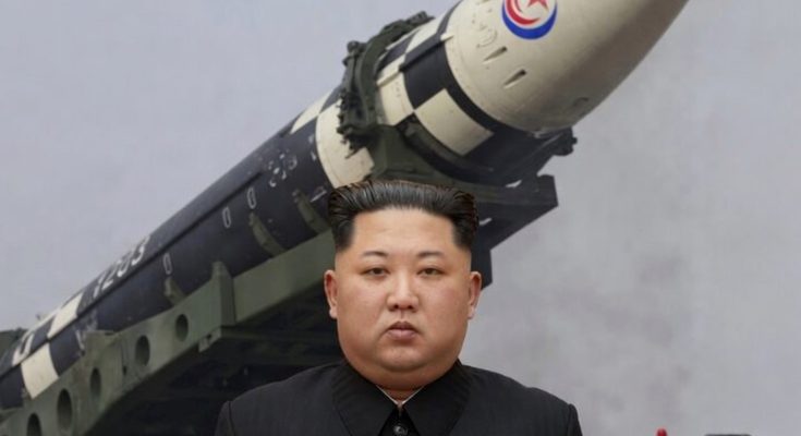 leader stands before large missile with military vehicle in background