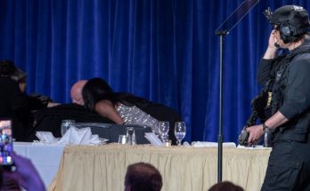security personnel in tactical gear at formal event, blue curtain backdrop
