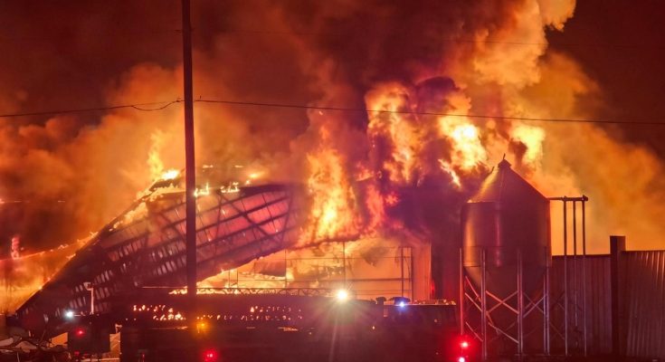 massive fire engulfs large industrial warehouse at night