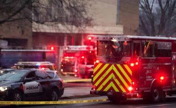 fire truck with chevron stripes and police SUV behind yellow crime scene tape at dusk