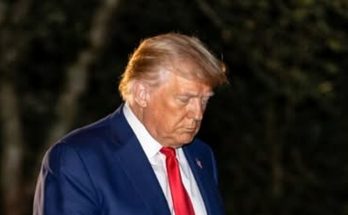 man in blue suit with red tie walking outdoors at night