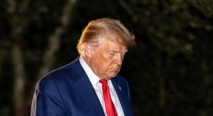 man in blue suit with red tie walking outdoors at night