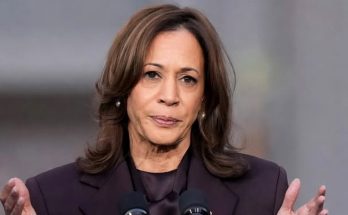woman in purple suit speaking at outdoor event