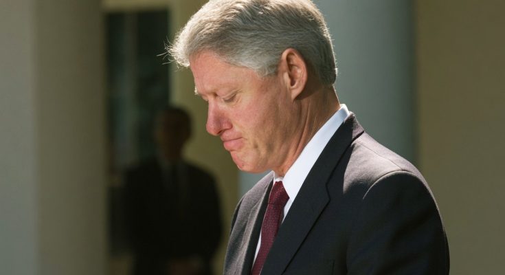 man in suit looking down, solemn expression, outdoor setting