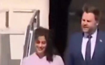 two people exit a plane smiling, formal attire, sunny day