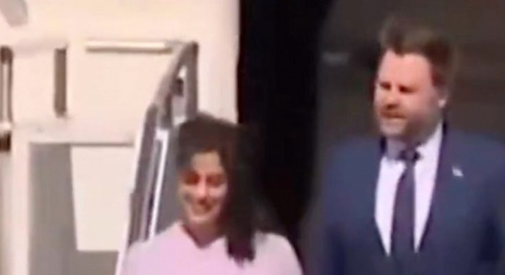 two people exit a plane smiling, formal attire, sunny day