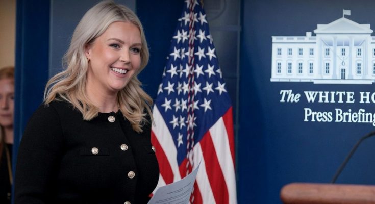 woman smiling at White House press briefing podium with flag backdrop
