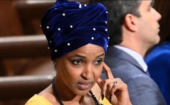 woman in blue turban with pearls, thoughtful expression, seated indoors