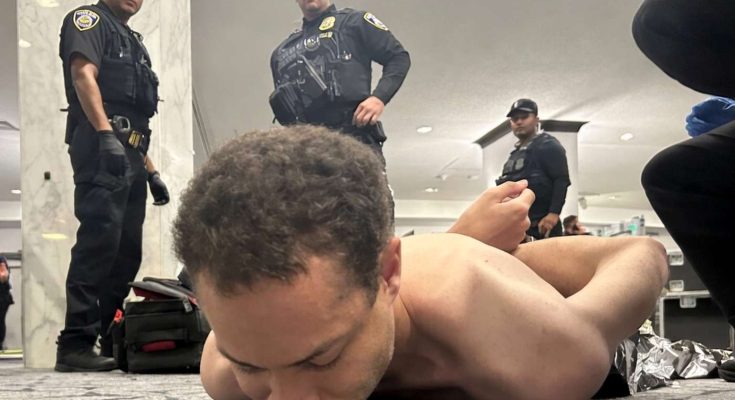 police officers detain man in public building, tense situation captured
