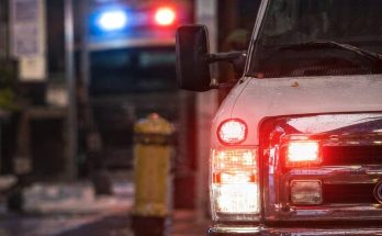 emergency vehicle with flashing lights on city street at night