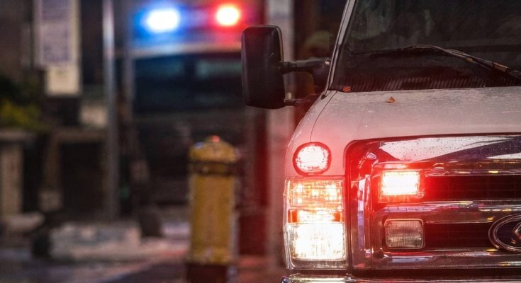 emergency vehicle with flashing lights on city street at night