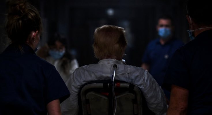medical team in masks escorting patient in dark corridor