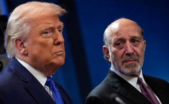 two men in suits at a formal event, serious expressions