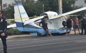 small plane crash lands on street with police and onlookers nearby