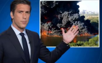 news anchor reports on massive fire with smoke cloud in background