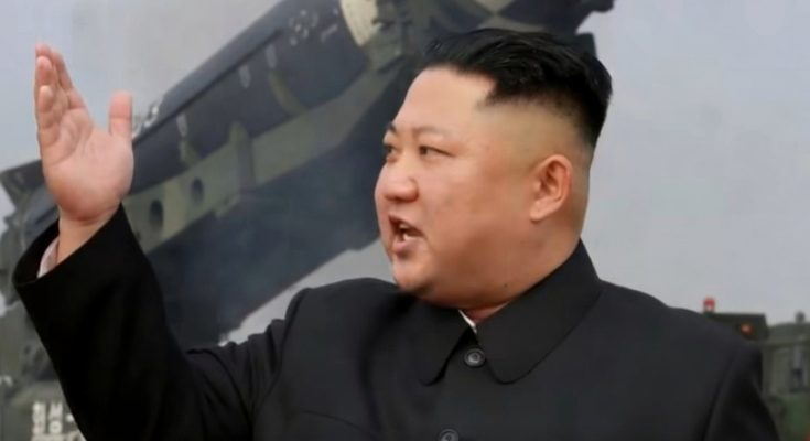 leader gestures beside large missile during military demonstration