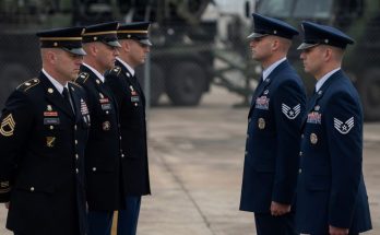military honor guard stands beside flag-draped coffin at ceremony