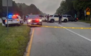 police cars block road amid emergency situation and reporter speaks