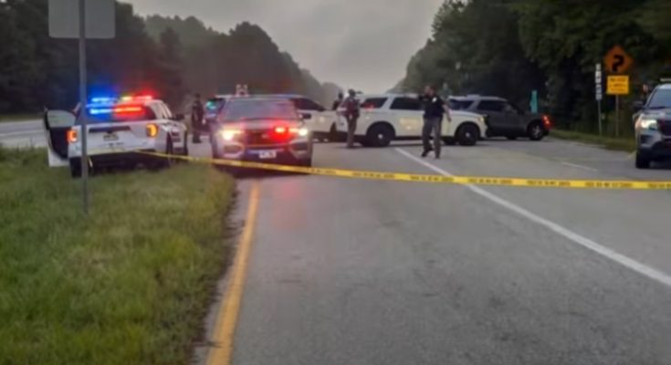 police cars block road amid emergency situation and reporter speaks