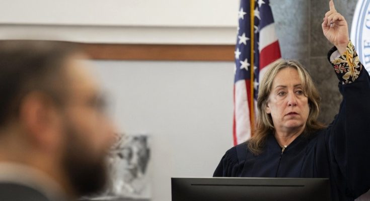 judge announces life sentence verdict in courtroom with flag
