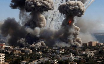 large explosions with smoke over city buildings under blue sky