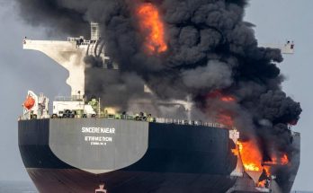 massive ship engulfed in flames and smoke on open sea